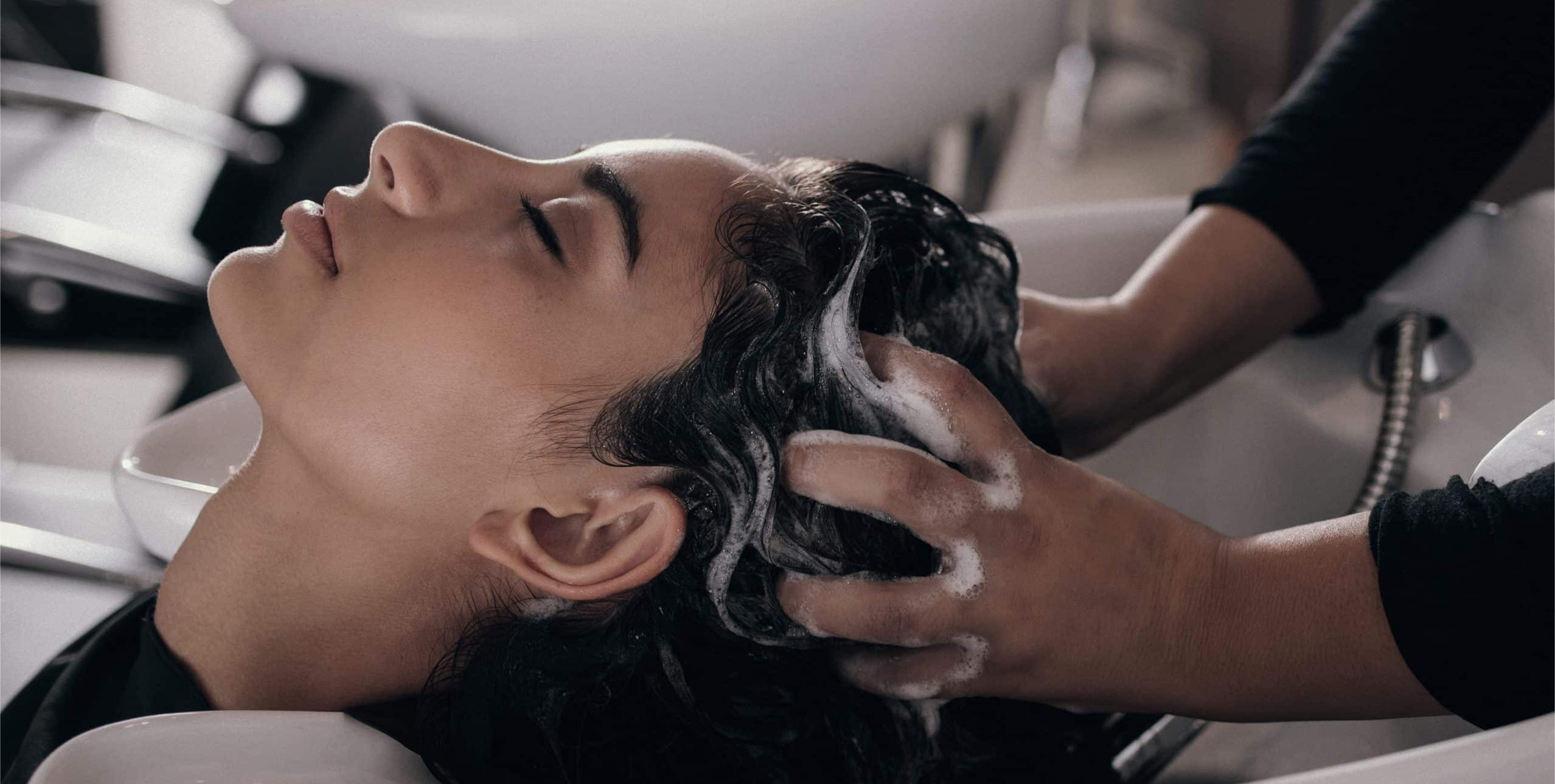 Woman receiving a scalp rinse while seated in a comfortable treatment chair, highlighting the beginning of her headspa treatment and the focus on effective scalp care in our japanese head spa at Oo Spa.