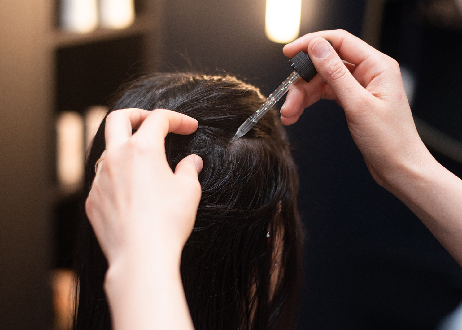 Close-up image of a woman receiving serum application to her scalp, showcasing the focus on effective scalp care during her treatment at Oo Spa.