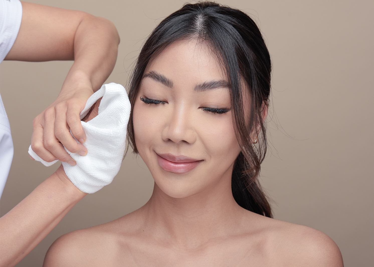 Smiling woman enjoying her facial massage during a rejuvenating treatment at Oo Spa, highlighting relaxation and the luxurious experience of the facial.